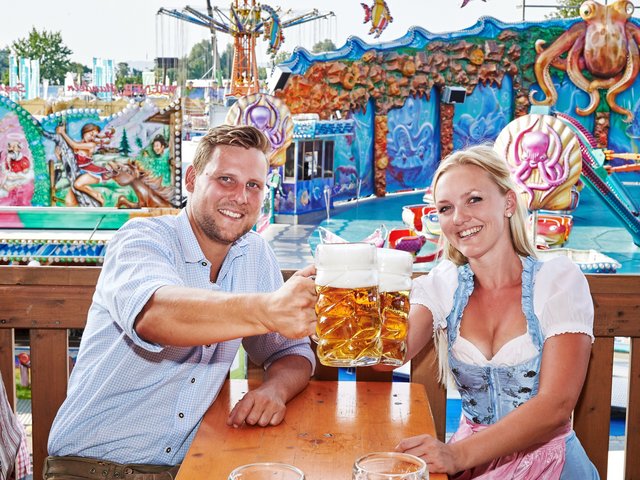 Anstoßen mit einer Maß Bier auf einem Volksfest 