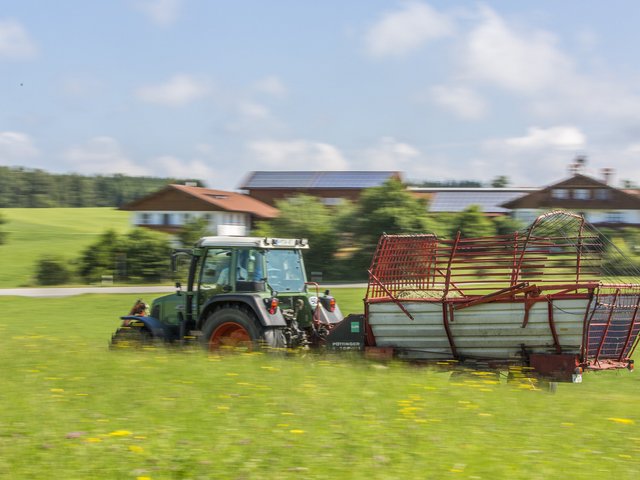 Traktro mit Ladewagen auf der Wiese 