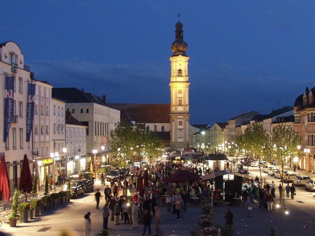 Sicht auf den beleuchteten Luitpoldplatz bei Nacht   an dessen Ende der Kirchenturm zu sehen ist 