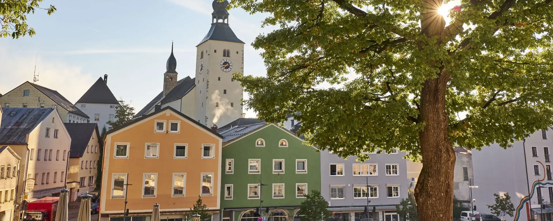Blick vom Stadtplatz Regen auf die farbige Häuserfront im Hintergrund die Stadtpfarrkirche